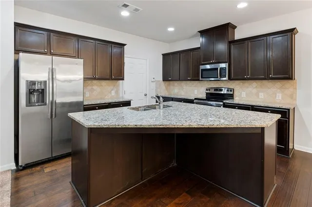 a kitchen with granite countertop stainless steel appliances a refrigerator a stove a sink and a center island