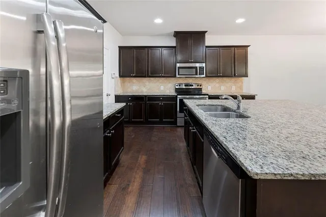 a kitchen with stainless steel appliances granite countertop a refrigerator a sink a stove and oven