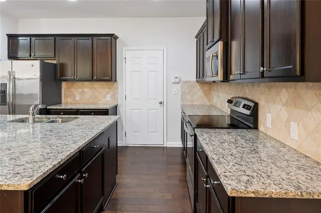 a kitchen with granite countertop kitchen island stainless steel appliances a sink stove and refrigerator