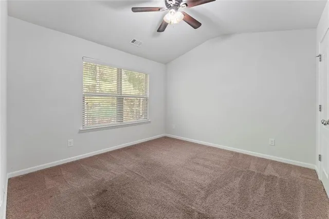 an empty room with chandelier fan and windows