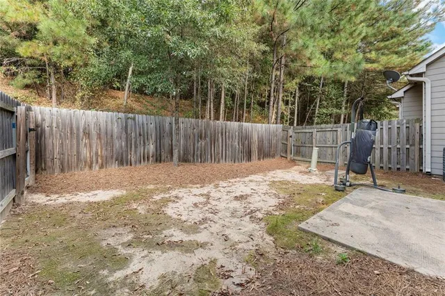 a backyard of a house with a tree and wooden fence