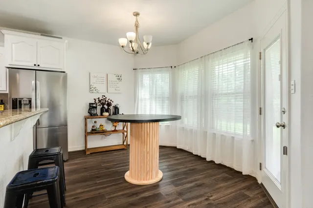 a dining room with wooden floor a chandelier a wooden table and chairs