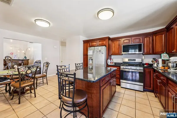 a kitchen with stainless steel appliances granite countertop a stove top oven a sink dishwasher a dining table and chairs with wooden floor