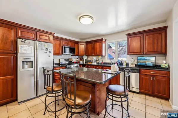 a kitchen with stainless steel appliances granite countertop a refrigerator a stove a sink a dining table and chairs with wooden floor