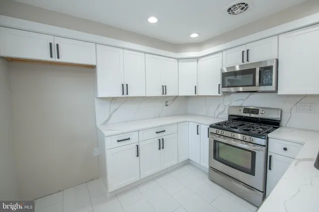 a kitchen with granite countertop white cabinets and stainless steel appliances