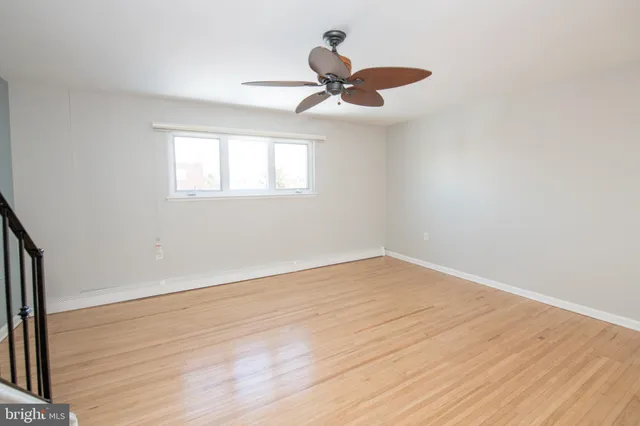 an empty room with wooden floor fan and windows