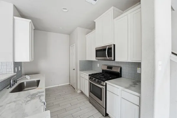 a kitchen with granite countertop a sink a stove and microwave