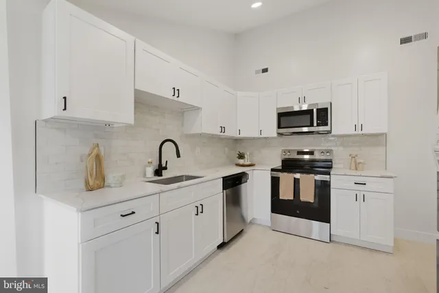 a kitchen with white cabinets a sink and appliances