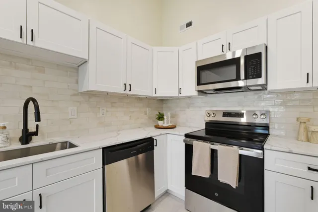 a kitchen with stainless steel appliances granite countertop white cabinets a sink and dishwasher