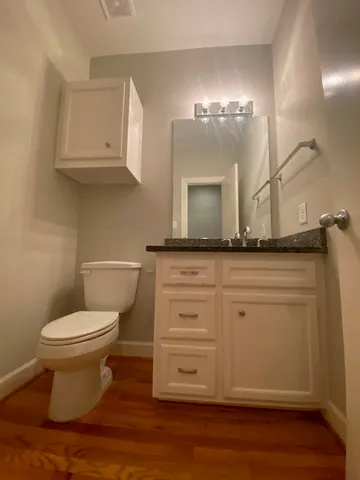 a bathroom with a granite countertop toilet sink and mirror