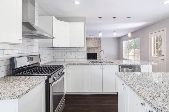 a kitchen with kitchen island granite countertop a sink stove and cabinets