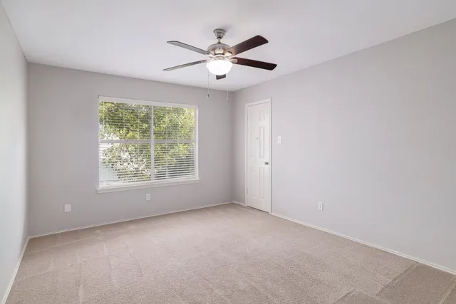 an empty room with a window and a fan