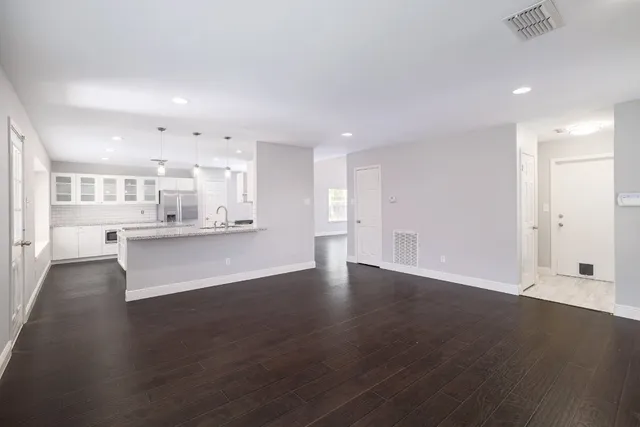 an empty room with wooden floor and windows