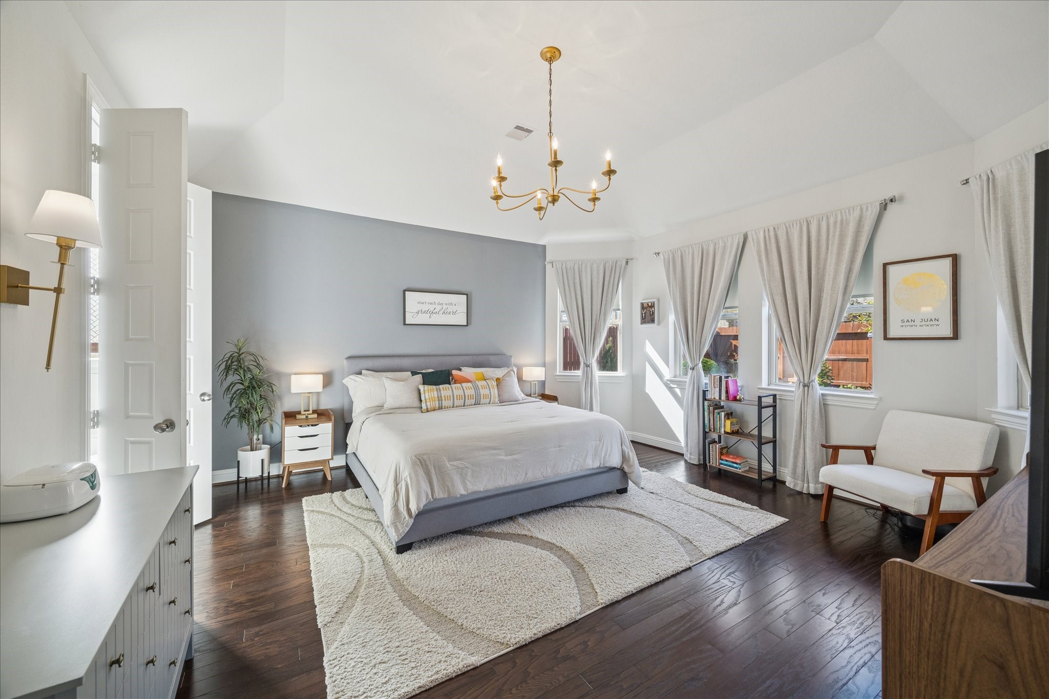 25214 Dewstone Way Porter, TX 77365 - Photo 29 of 29 Spacious and elegant primary bedroom is on the other back side of the home giving a split floor plan. Warm rich wood flooring continuing in this beautiful space. Window sheers and a painted accent wall give an elegant touch.