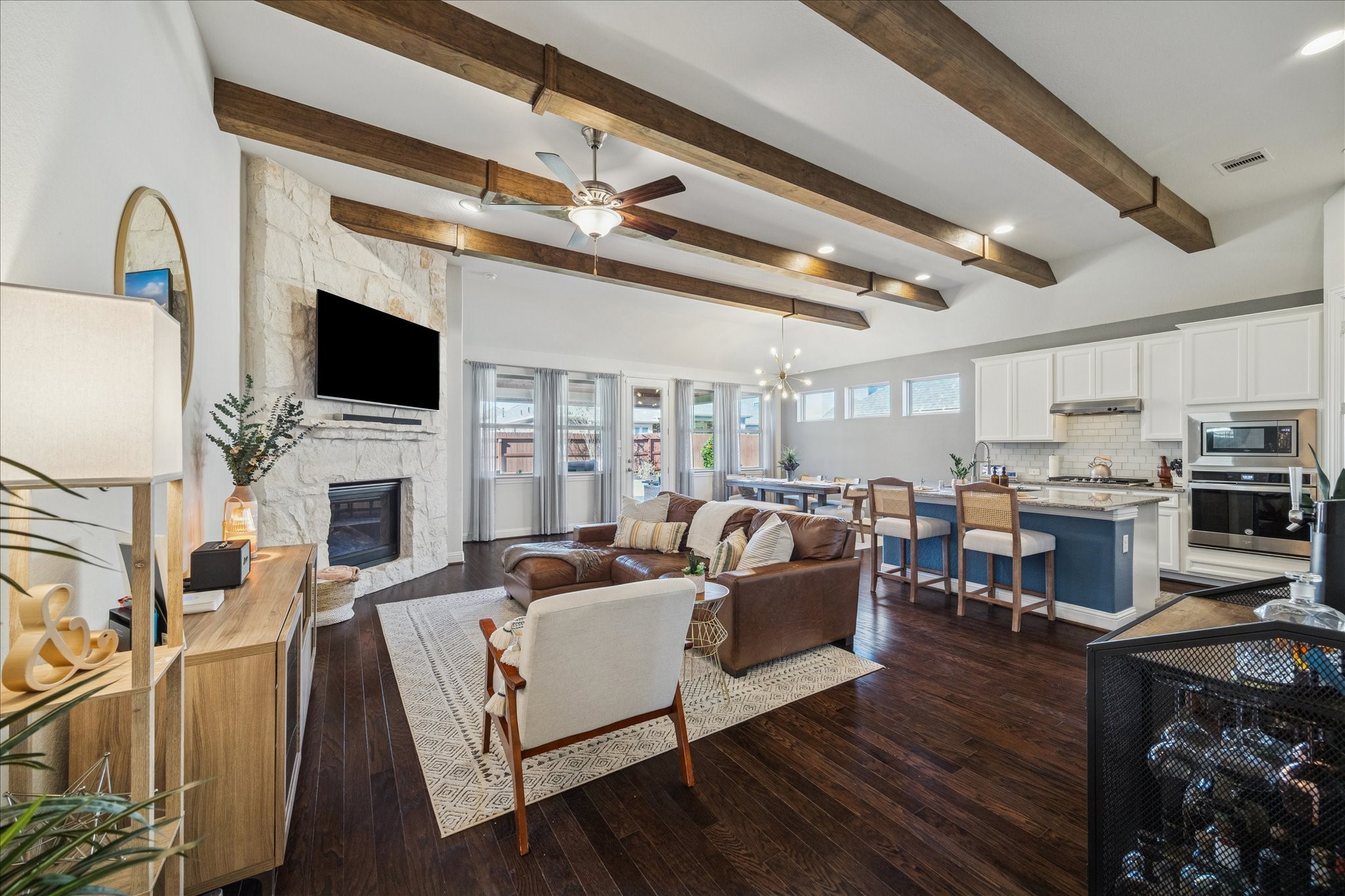 25214 Dewstone Way Porter, TX 77365 - Photo 6 of 29 This stunning open concept living space seamlessly blends style and functionality. Dramatic wood ceiling beams and rich wood flooring give so much warmth and comfort. The stone fireplace also keeps with this cozy and elegant style. Your TV can be featured on the Fireplace like they currently have it or on the large wall on the left.