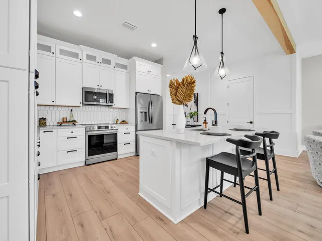 a kitchen with stainless steel appliances a stove a sink and white cabinets with wooden floor