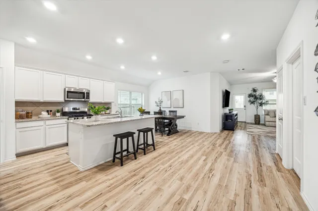 a living room with furniture and kitchen view with wooden floor