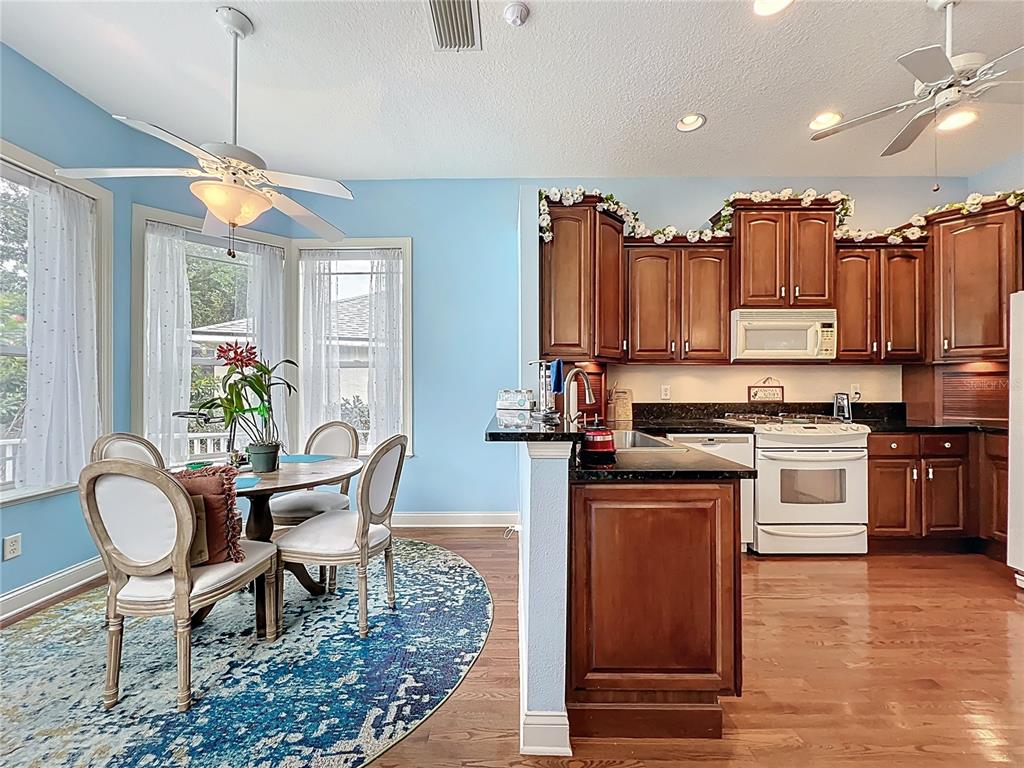 214 Chestnut Ridge Street Winter Springs, FL 32708 - Photo 23 of 68 a kitchen with stainless steel appliances granite countertop a stove top oven a sink dishwasher a dining table and chairs with wooden floor