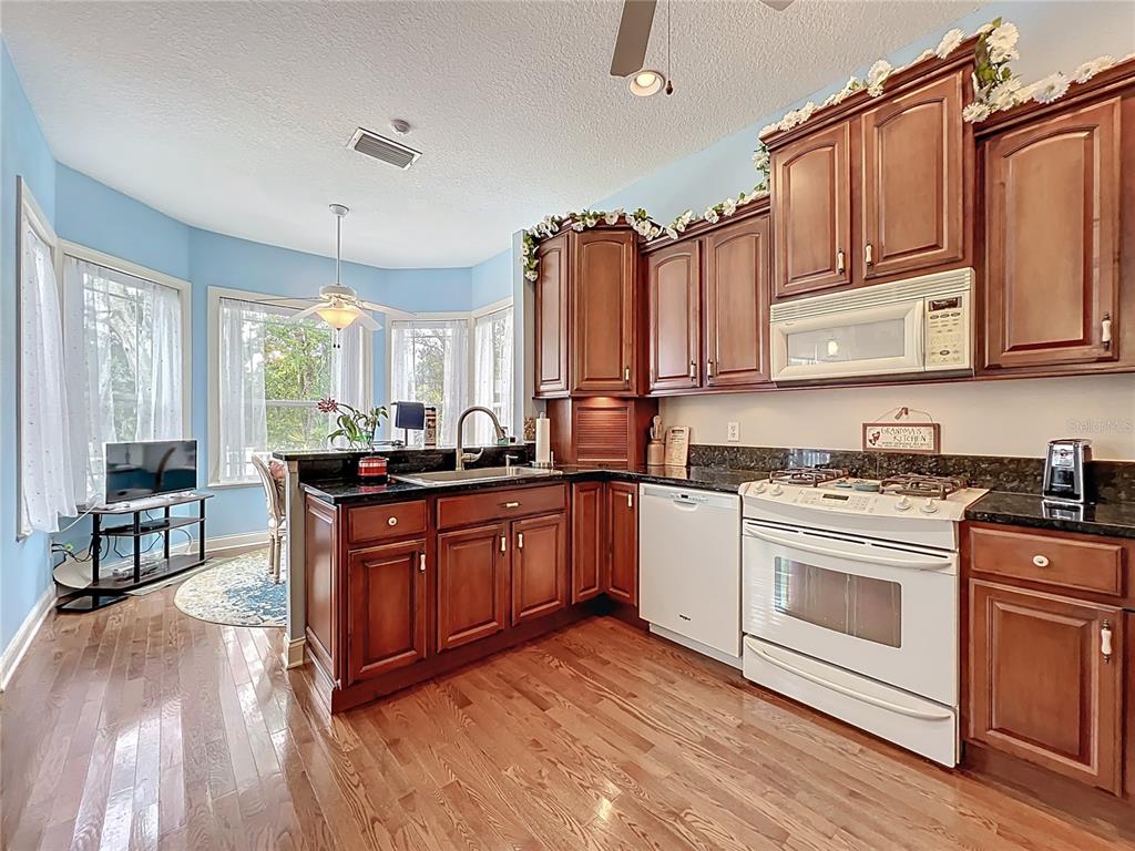 214 Chestnut Ridge Street Winter Springs, FL 32708 - Photo 25 of 68 a kitchen with stainless steel appliances granite countertop a stove a sink dishwasher and wooden cabinets with wooden floor