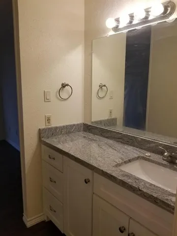a bathroom with a granite countertop sink and a mirror