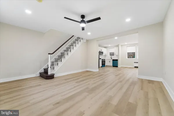 a view of an empty room with wooden floor and a ceiling fan