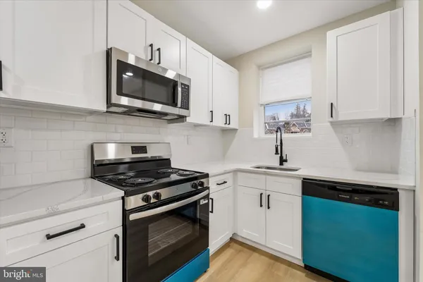 a kitchen with stainless steel appliances granite countertop a sink dishwasher a stove and a microwave oven with cabinets