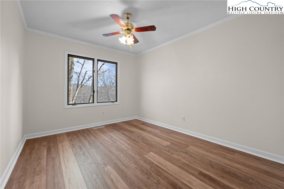 131 Hemlock Road Banner Elk, NC 28604 - Photo 14 of 37 an empty room with wooden floor chandelier fan and windows