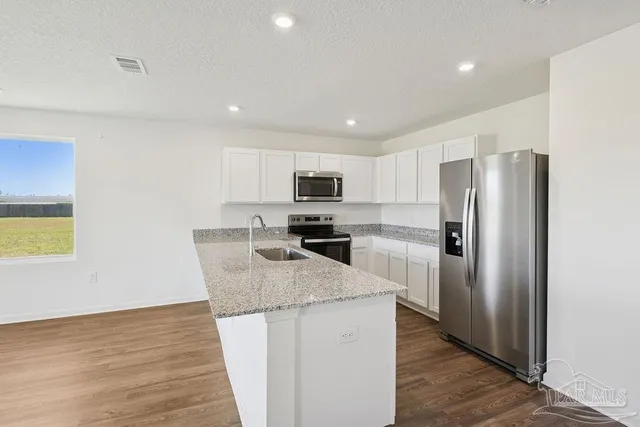 a kitchen with granite countertop a refrigerator and a sink