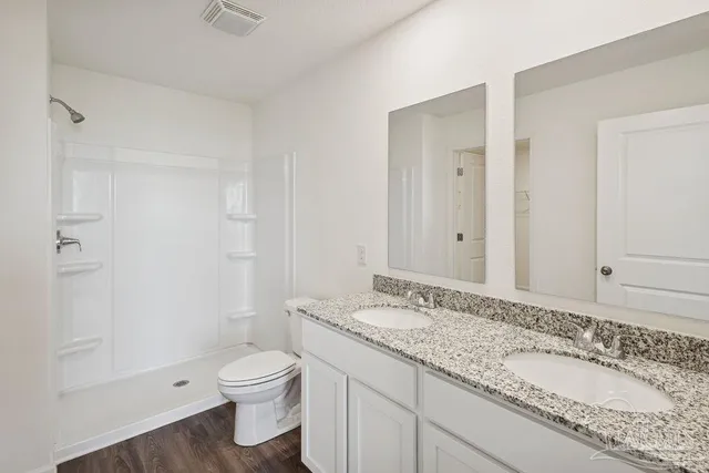 a bathroom with a granite countertop toilet a sink and a mirror