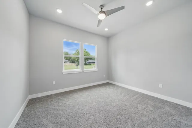 en empty room with windows and ceiling fan