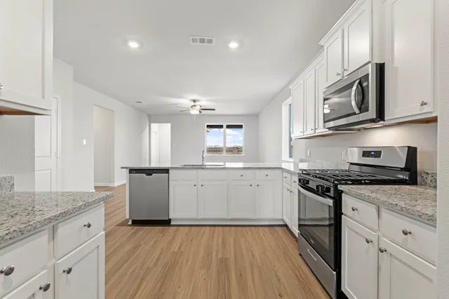 a kitchen with granite countertop cabinets stainless steel appliances and a wooden floor