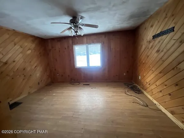 en empty room with windows and chandelier fan