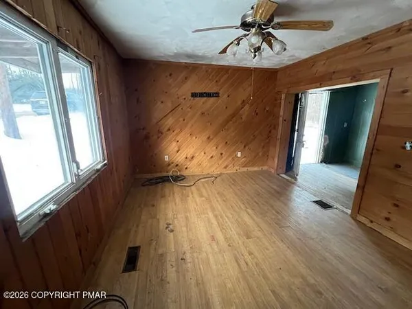 a view of empty room with wooden floor and fan