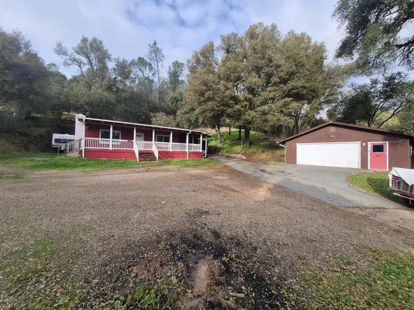 a view of a house with backyard and trees