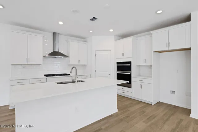 a view of empty room with wooden floor and kitchen