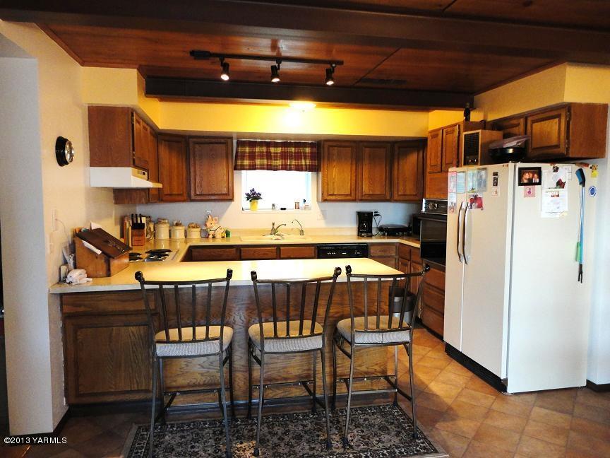 6408 Postma Road Yakima, WA 98901 - Photo 9 of 25 a kitchen with stainless steel appliances granite countertop a stove a refrigerator a sink a dining table and chairs with white cabinets