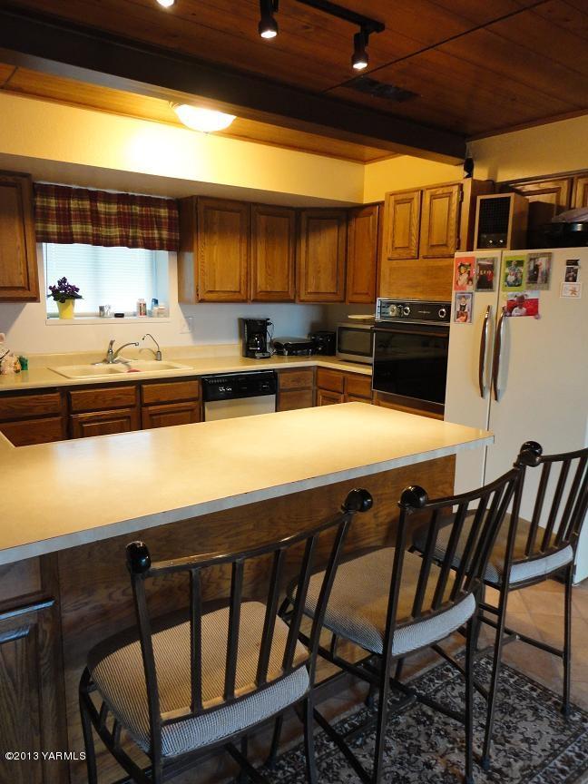6408 Postma Road Yakima, WA 98901 - Photo 10 of 25 a kitchen with stainless steel appliances kitchen island granite countertop a table and chairs in it