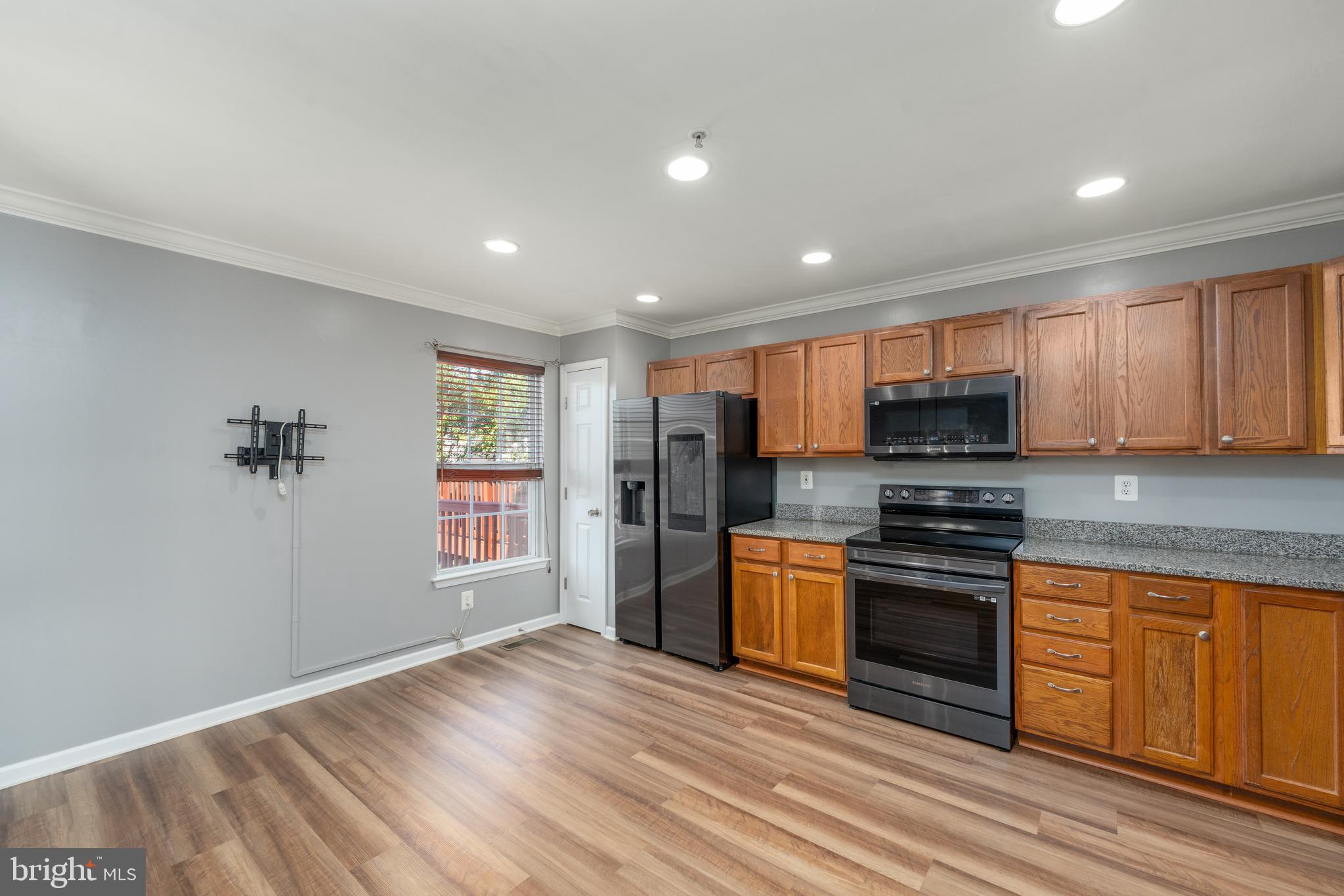 9903 Decatur Road Baltimore, MD 21220 - Photo 22 of 37 a kitchen with stainless steel appliances granite countertop a refrigerator a stove top oven a sink and dishwasher with wooden floor