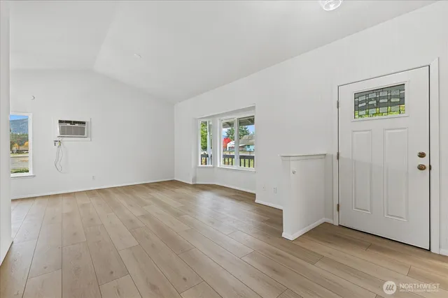 an empty room with wooden floor window and windows