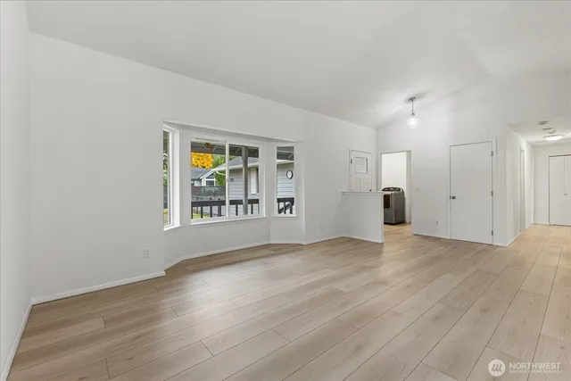 a view of an empty room with window and wooden floor