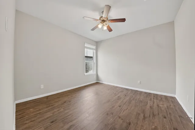 an empty room with wooden floor and ceiling fan