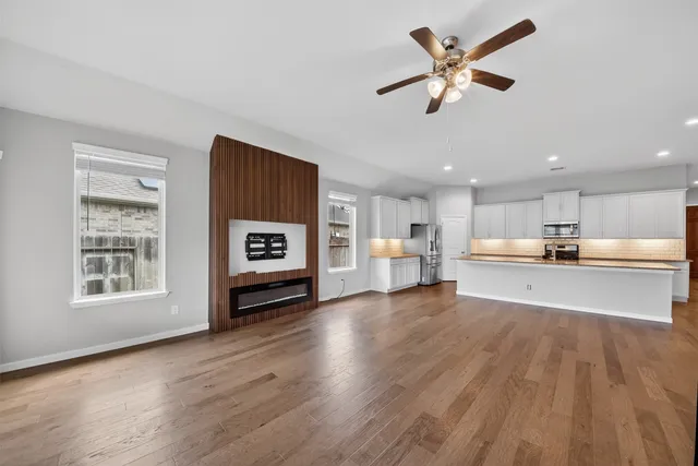a view of an empty room with a window and wooden floor