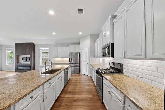 a large kitchen with stainless steel appliances granite countertop a lot of counter space and wooden floor