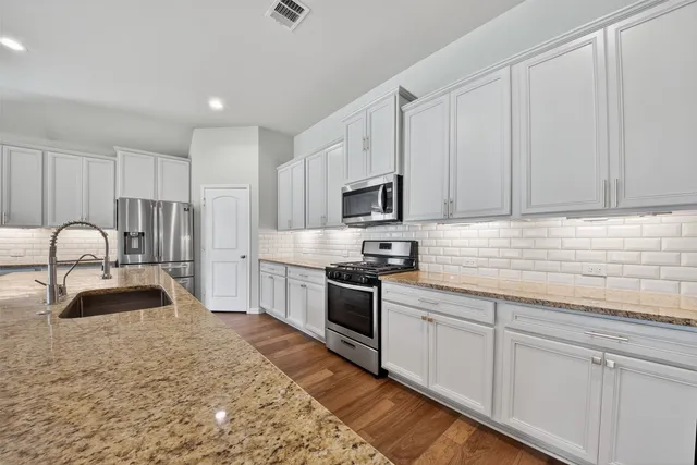 a kitchen with granite countertop white cabinets and stainless steel appliances