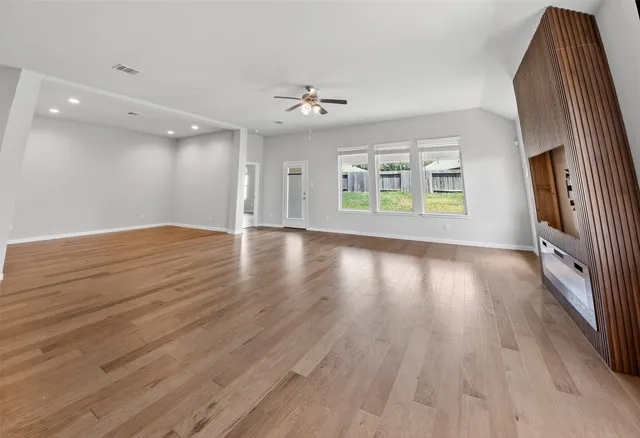an empty room with wooden floor and windows