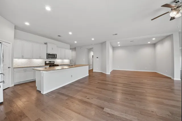 a large white kitchen with kitchen island a sink stainless steel appliances and cabinets