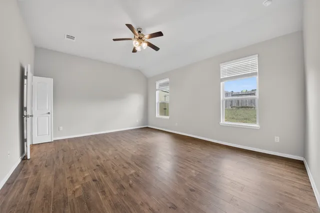 a view of an empty room with a window and wooden floor