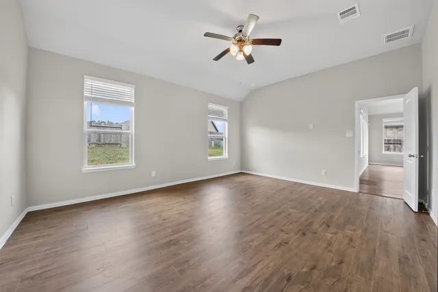 a view of an empty room with a window and wooden floor