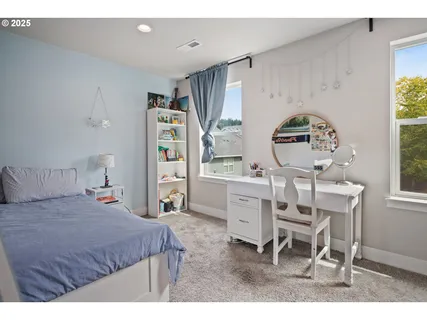 a bedroom with a bed a desk and chair with window