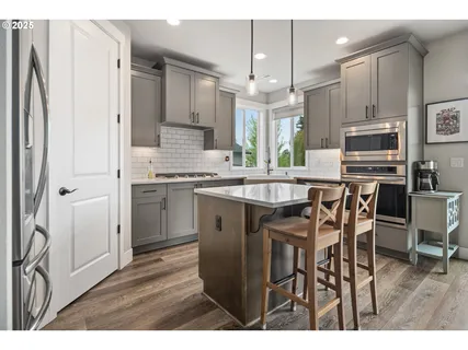 a kitchen with stainless steel appliances a dining table chairs refrigerator and sink